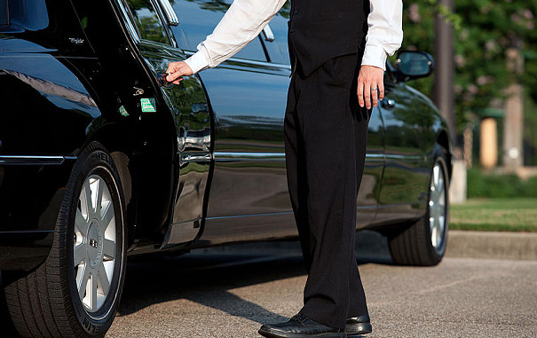 a professional chauffeur opening a door of a limousine